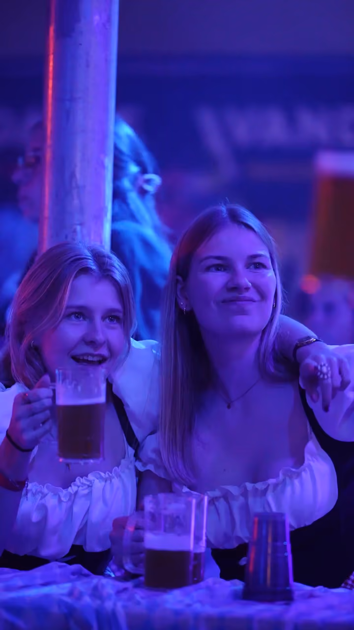 Twee bezoekers met bierpullen in blauw en roze licht