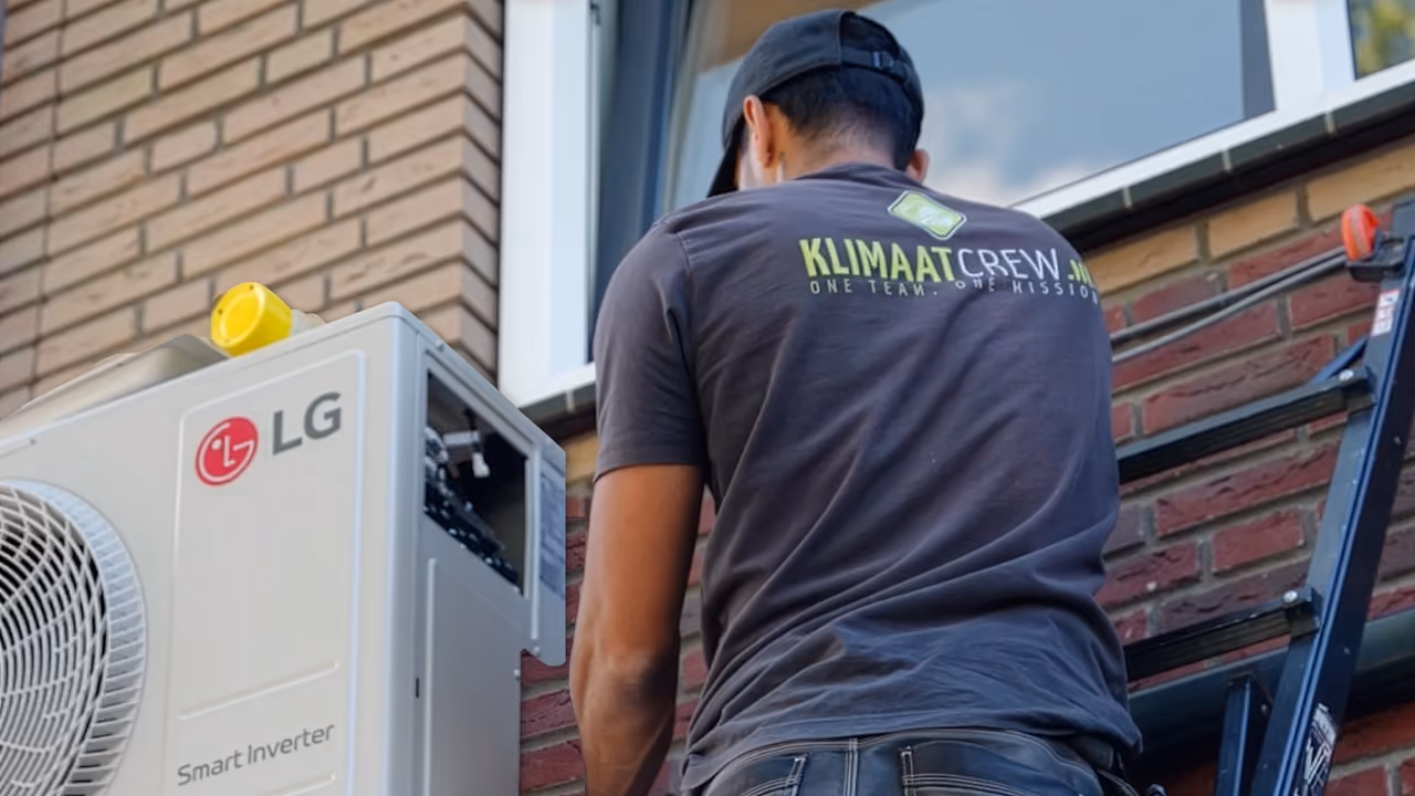 Monteur van KlimaatCREW op een ladder bij een buitenunit van een airco tegen een gevel